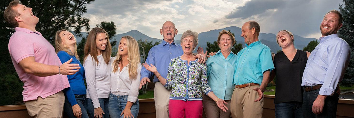 Portrait of a multigenerational family on deck, laughing, in front a cloudy sunset sky